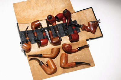 Image Pipe shelf and 22 branded pipes, branded pipes inter alia 5 x Dunhill, Nording, Briar, Bang, 3 x Savinelli, Killarmey, Vauens, Dansk and Peterson, inter alia, in addition one Meerschaum pipe, all used, partly with traces of usage, corner shelf in oak with floral carving, in addition slightly accessories, 84 x 35 cm, Thigh depth 25 cm in addition tobacco vessel, two pipes without mouthpiecee